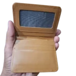 Tan leather wallet held in hand, showing interior card compartments and clear ID window wolveyes